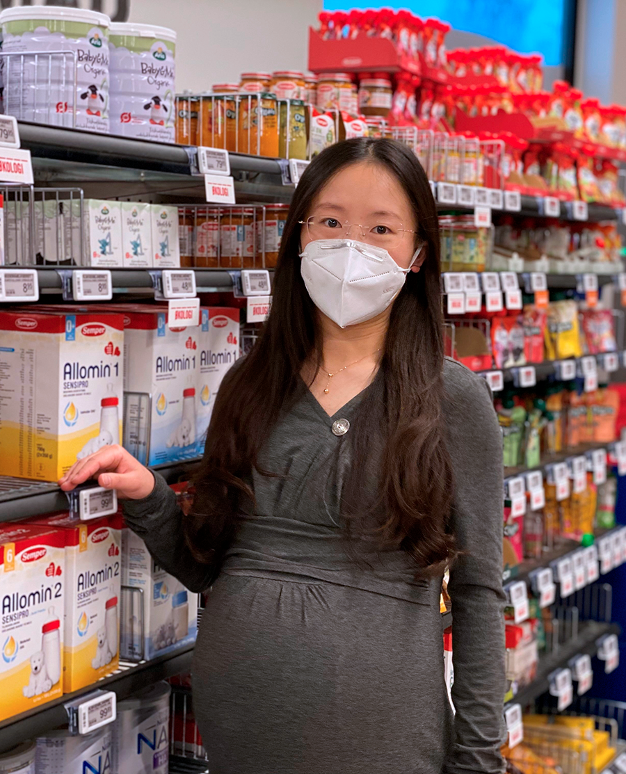 Kvinde i supermarked, modermælkserstatning på hylder i baggrunden